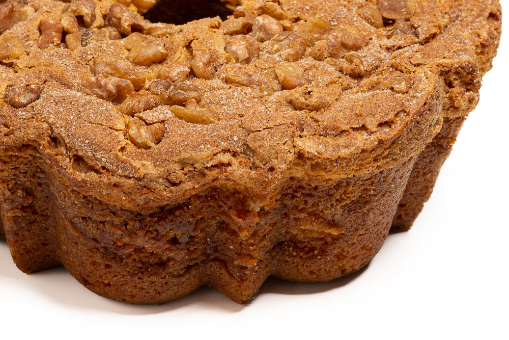 A traditional cinnamon walnut coffee cake with a golden brown color and a layer of chopped walnuts on top.